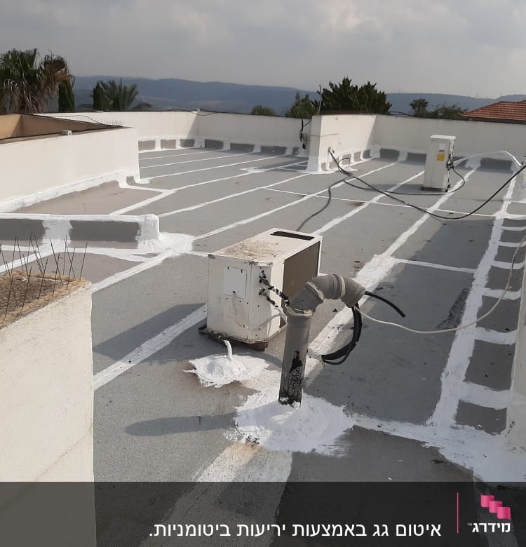 איטום גג עם חומר לבן סביב צינורות ומזגנים